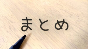 木目状の板に「まとめ」の文字とボールペン