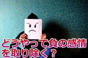 怒っている絵を顔の前に掲げた男性と「どうやって負の感情を取りのぞく？」の文字